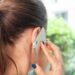 5G-Mobilfunkmast sendet Strahlung aus, darunter ein Smartphone mit Warnsymbol für potenzielle Gesundheitsrisiken