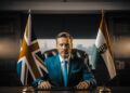 Neue Agentur-Lösung: Trading House aus Ungarn 8 Geschäftsmann am Schreibtisch zwischen britischer und ungarischer Flagge – Symbolbild für Trading House